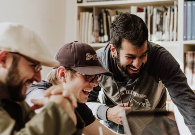 Three people looking at a screen laughing